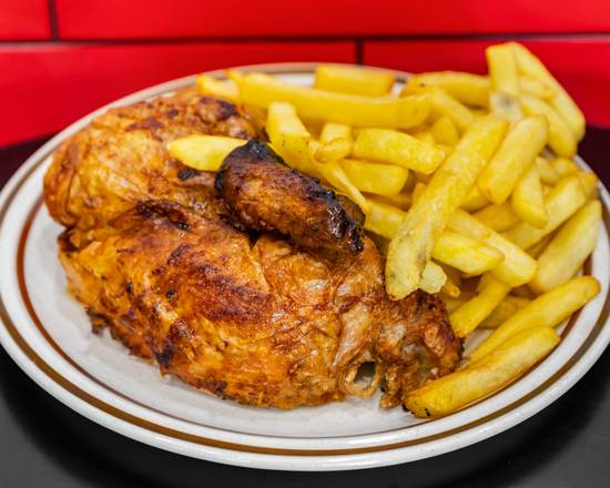 Charcoal chicken with golden skin beside a heap of chips