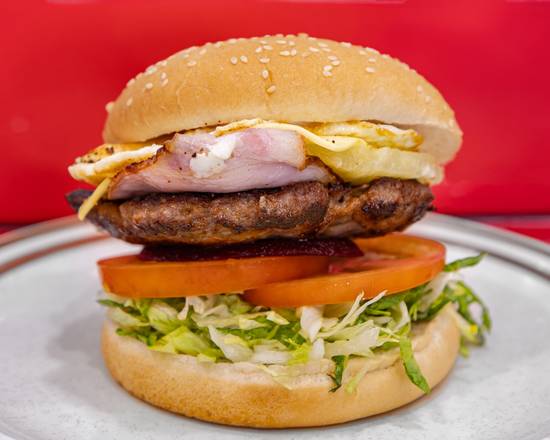 A hamburger stacked with a beef patty, bacon, egg, tomato, beetroot and lettuce