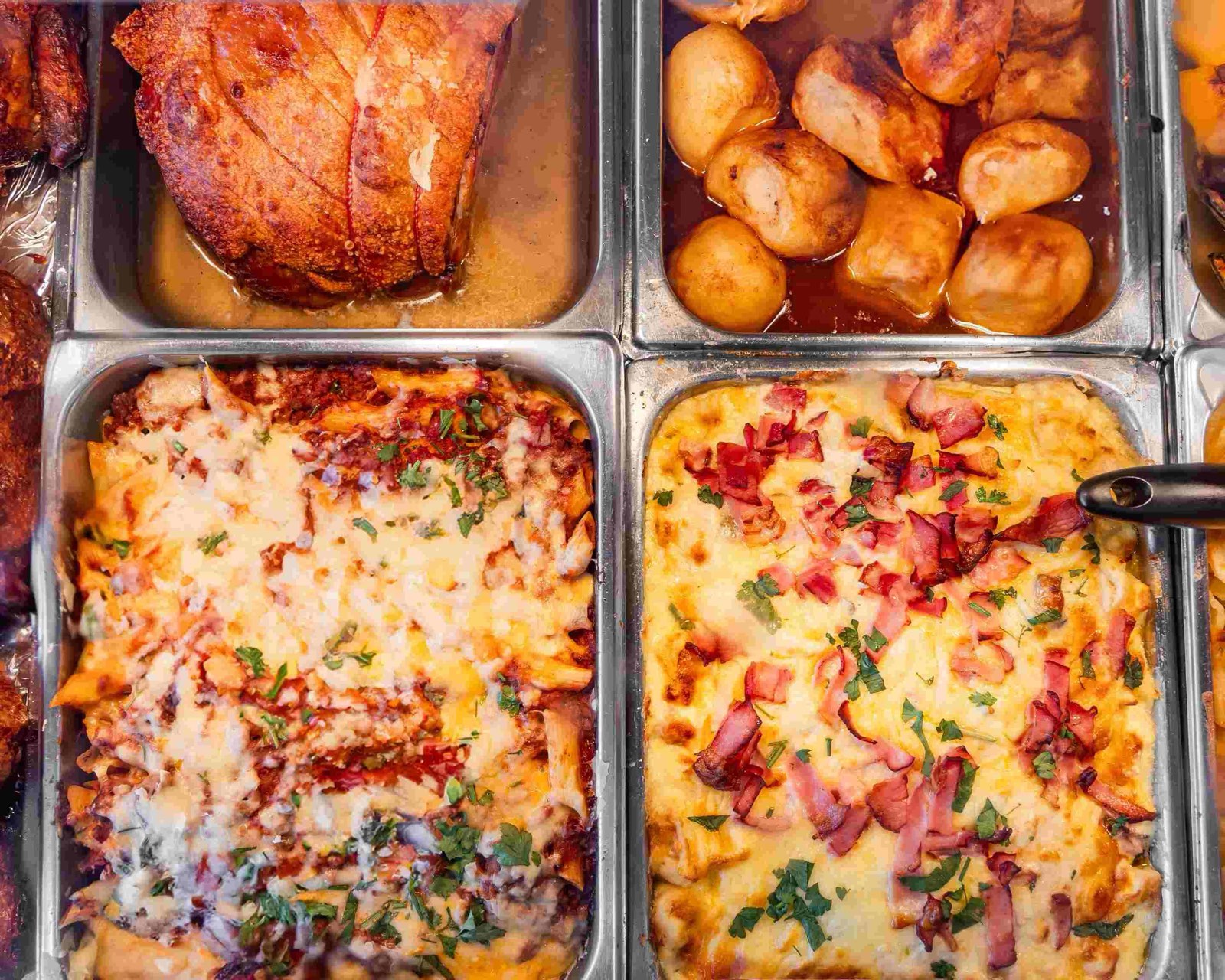 Trays on the hot bar: penne bolognese under melted cheese, and a creamy potato bake topped with bacon